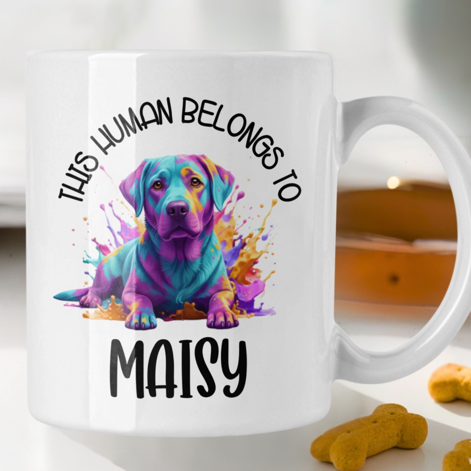 White mug with a colorful dog illustration and text 'This human belongs to Maisy' on a white background.