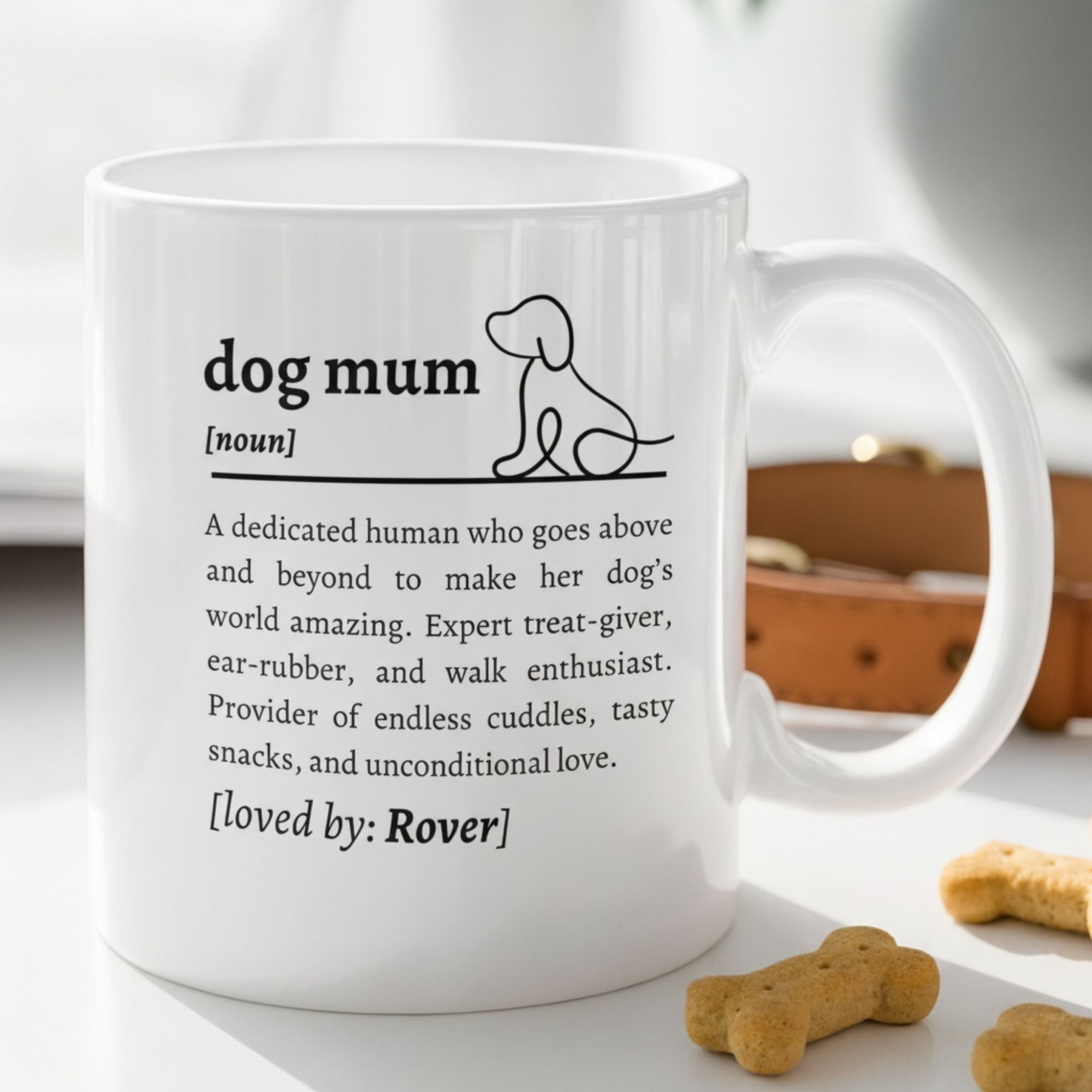 White mug with text about 'dog mum' on a surface with dog treats.