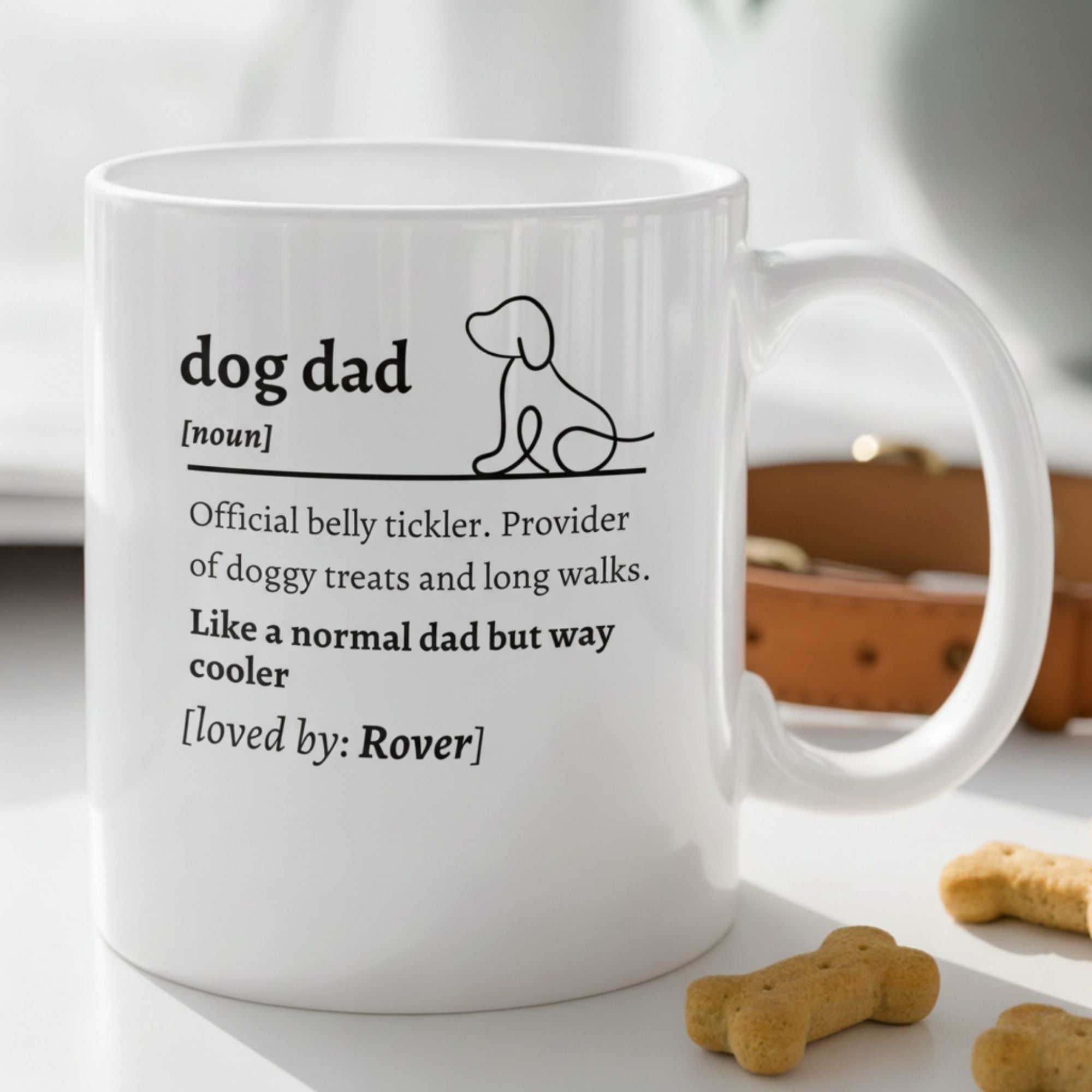 White mug with text about 'dog dad' on a surface with dog treats.
