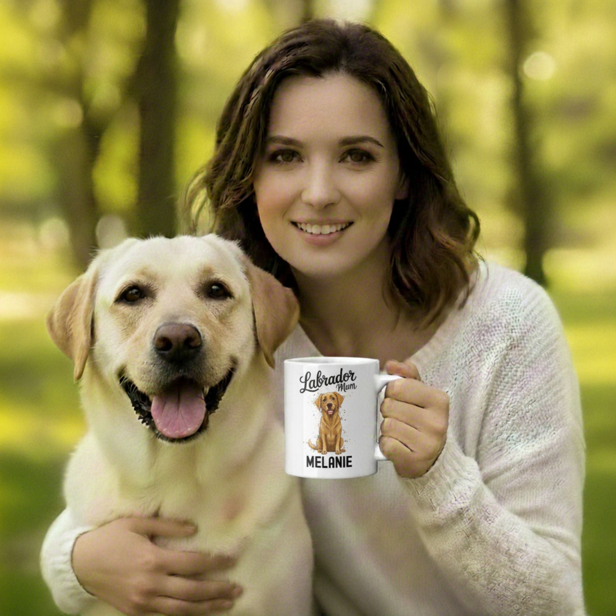 Woman holding a mug with a Labrador illustration and text, standing in a forest.